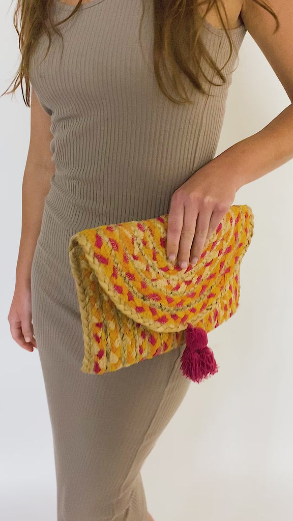 Woman in tan knit bodycon dress models a handmade clutch bag with recycled cotton lining
